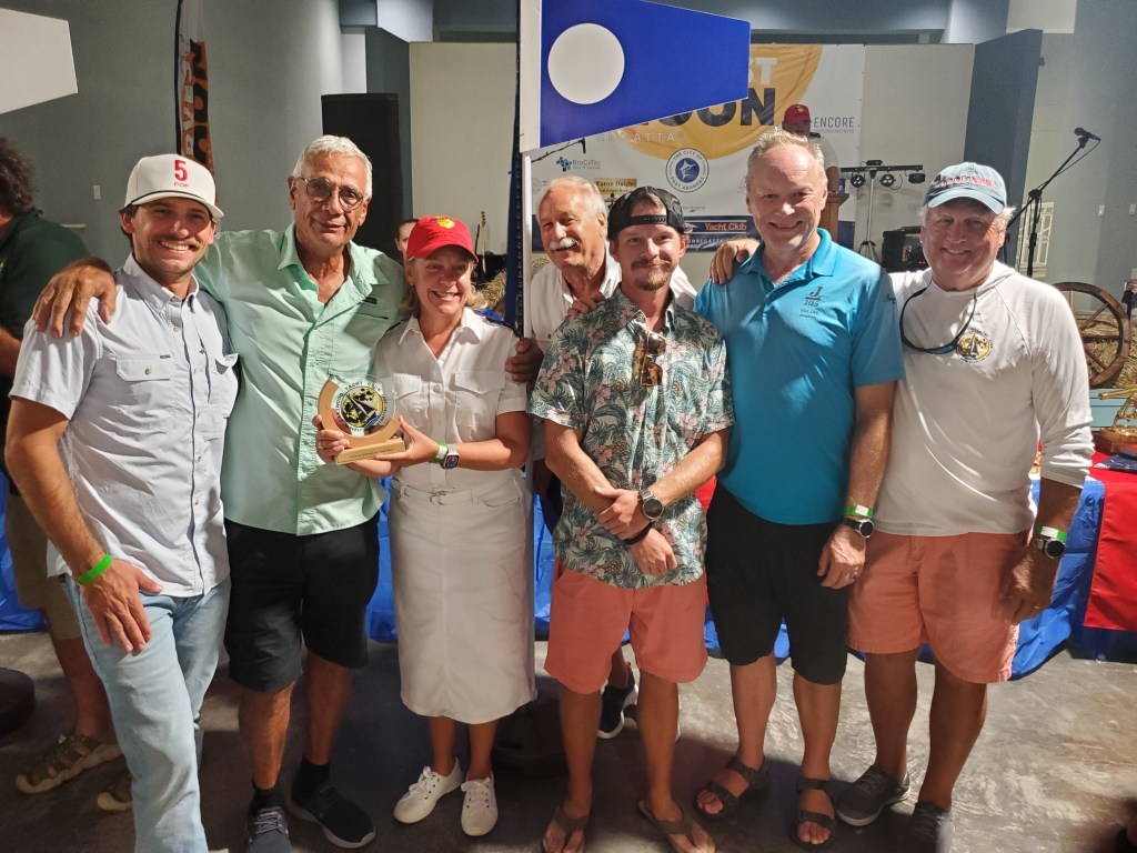 Winning crew posing with their trophy and flag at the Harvest Moon Regatta awards ceremony