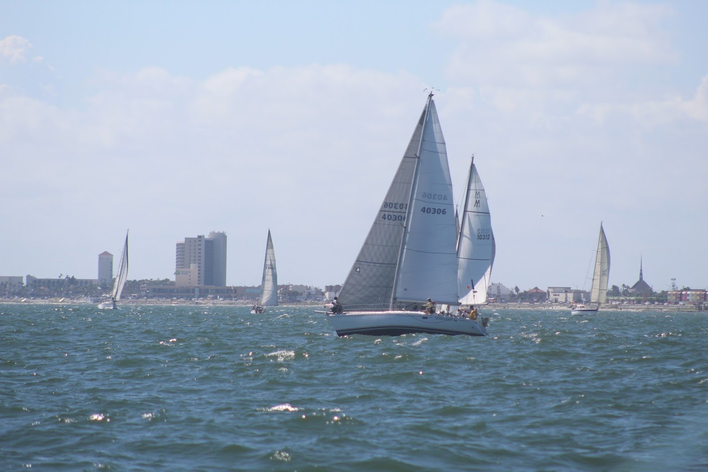 Sailboats sailing together in the Gulf during the Harvest Moon Regatta